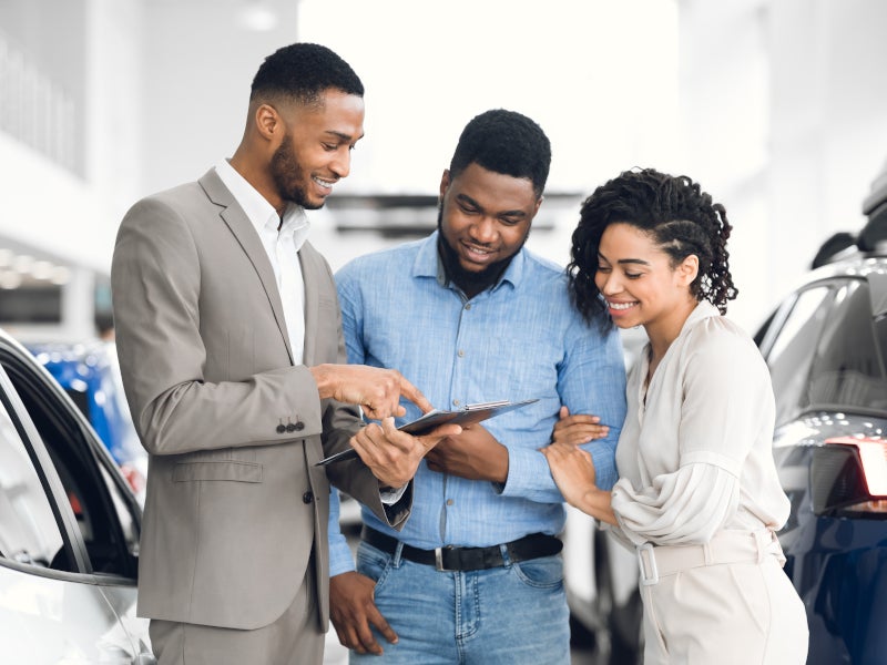 Sales consultant showing a clipboard to a smiling couple in a showroom