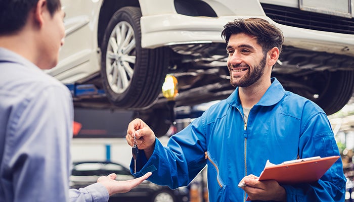 Smiling mechanic returning car keys to a customer in a repair shop